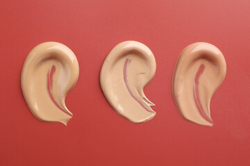 Samples of foundation on red background, flat lay