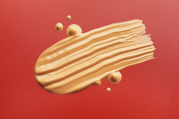 Samples of foundation on red background, closeup