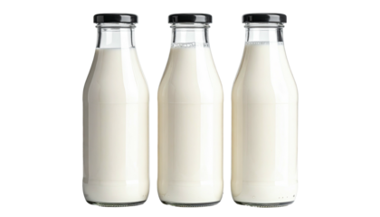 Three glass bottles filled with white liquid against dark background