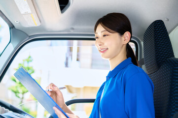 運転席で点検する女性ドライバー　トラック　配送