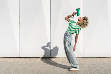Young woman bending backwards and speaking through megaphone
