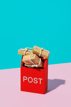 Miniature mailbox toy with stacked parcels on pastel pink and blue background