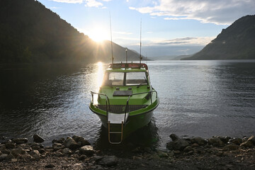 The motorboat is moored to the shore of a picturesque mountain lake