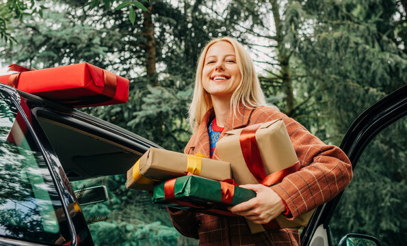Smiling woman with Christmas gifts returning home outdoors