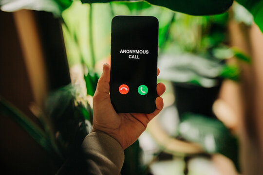 Anonymous call appearing on smartphone held in hand with scam alert