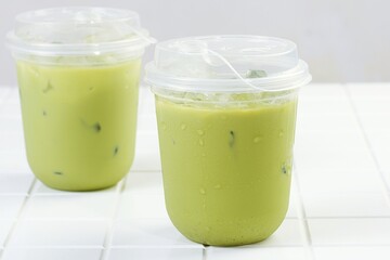 Iced matcha green tea served in plastic cup isolated on white table. Great for cafe lifestyle, fresh drink, or healthy concept.
