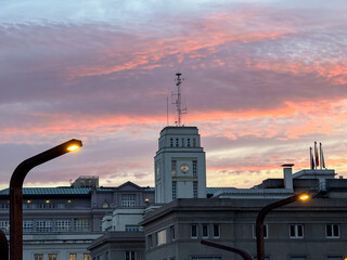 Clock tower and streetlights at dusk over city rooftops