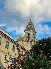 Stone bell tower rising over historic courtyard with flowers