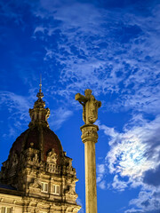 Stone cross and historic dome at twilight with clouds