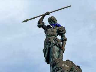 Bronze statue of woman raising spear against sky