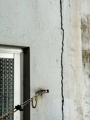 Vertical crack on exterior plaster wall near window