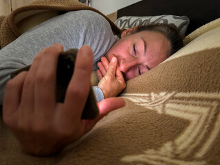 Adult lying in bed using smartphone at night