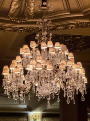 Crystal chandelier illuminating ornate ceiling in grand interior