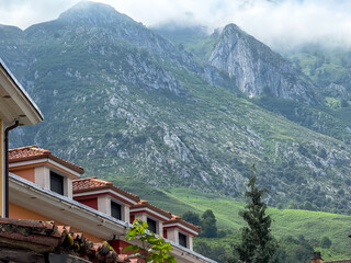 Mountain slopes rising behind village rooftops in mist