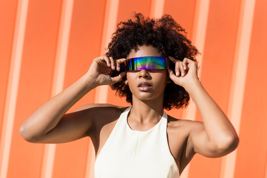 Fashionable woman with afro hairstyle wearing colorful sunglasses outdoors