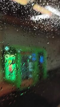 Raindrops creating abstract texture on RER A window, blurring urban lights into bokeh.