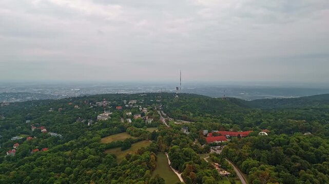 Aerial hyperlapse from Budapest, Normafa, flying toward the Sz&eacute;chenyi-hegyi transmission tower under a cloudy sky in Hungary.