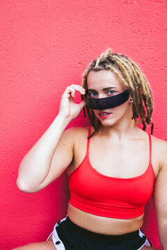 Portrait of strong woman with dreadlocks in red sportswear outdoors