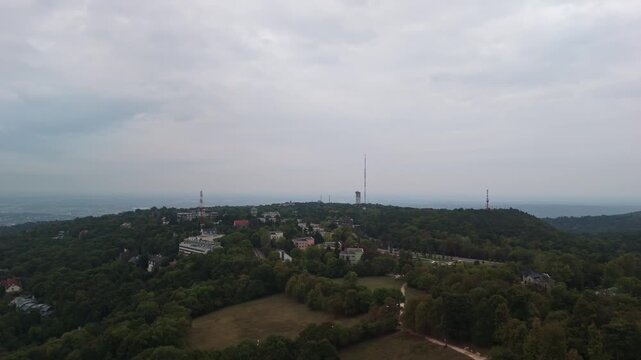 Orbital drone view from Normafa with the surrounding radio towers on the Sz&eacute;chenyi-hegy under a cloudy sky in Hungary.
