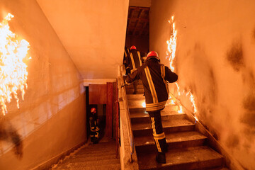 Firefighters in action, climbing stairs amidst flames and smoke, showcasing bravery and emergency...