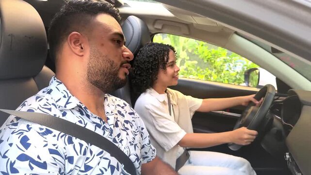 Driving instructor giving a lesson to a young female student, talking and gesturing inside a car - Powered by Adobe