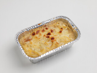 Baked macaroni and cheese in aluminum foil on white background