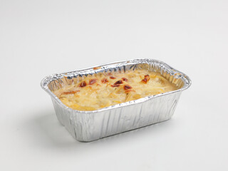 Baked macaroni and cheese in aluminum foil on white background