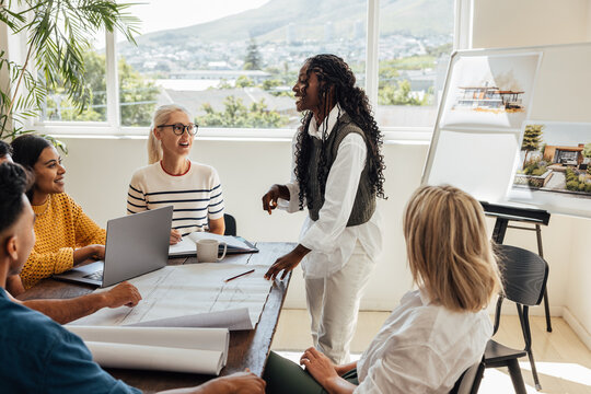 Young architects discussing plans and designs during a design team meeting