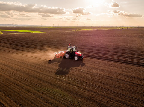 Farming tractor seeding field during sunset aerial view