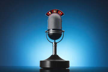 A vintage silver microphone on a stand against a blue studio backdrop.Radio, podcasting,...