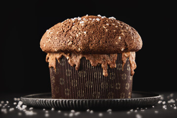 Christmas Italian cake panettone, soft traditional sweet bread with nuts, raisins and chocolate on black background