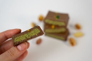 Hand presenting a pistachio chocolate bar on white background. Perfect for advertising, e-commerce, or food packaging mockups. 