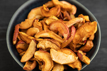 Dried Apples in ceramic bowl on black wooden. Side view, close up, selective focus
