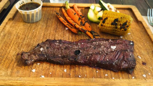 Skirt steak with grilled vegetables, corn, carrots and zucchini with sauce chimichurri. High quality 4k footage