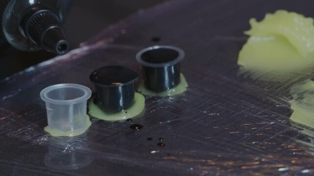 Tattoo artist pouring black ink into cap