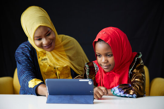 Muslim family, mother and daughter using a tablet on the table - Powered by Adobe