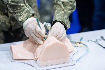 A man in military uniform conducts a master class on medical care on a mannequin