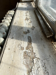 Old wooden window sill, peeling from paint, next to a cast-iron radiator