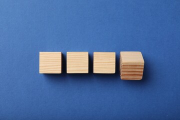 Wooden cubes on blue background, top view