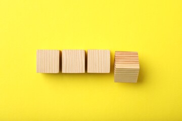 Wooden cubes on yellow background, top view