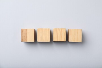 Wooden cubes on light background, top view