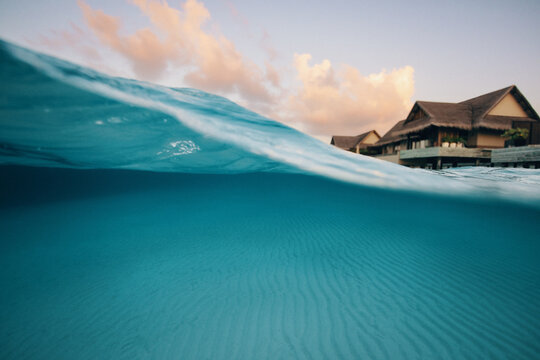 Seaside split shot view of villa with wave and turquoise water at tropical resort