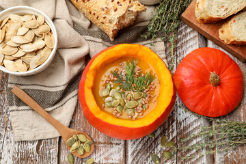 Tasty pumpkin cream soup with seeds, dill and thyme on color wooden table, flat lay