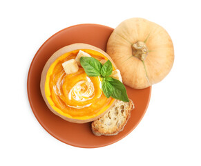 Tasty pumpkin cream soup with basil and bread served in pumpkin isolated on white, top view