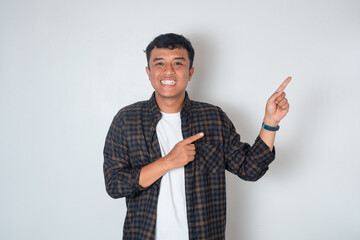 Happy and handsome young Asian man in casual shirt pointing left and smiling at camera isolated on white background