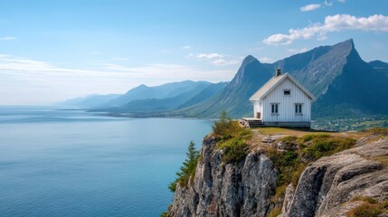 White house on a cliff overlooking the sea and majestic mountains. Scenic landscape with traditional Nordic cottage for travel and tourism.