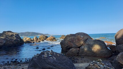 large coastal boulders and cairns on a rocky beach under a clear blue sky
