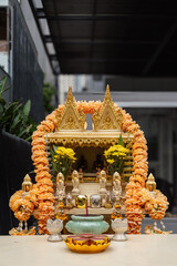 Gold Thai Spirit House with Offerings and Marigold Garlands in Bangkok, Thailand