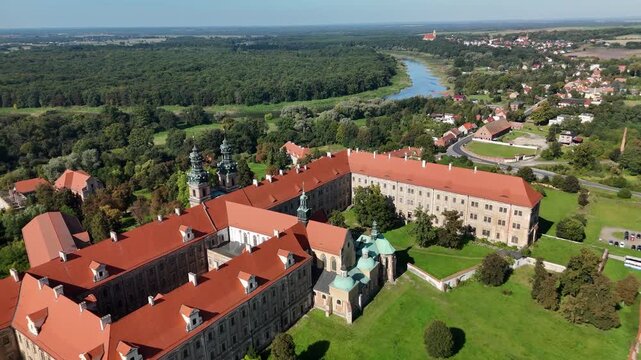 Aerial drone view of Cistercian Abbey in Lubiąż, Lower Silesia, Poland, surrounded by lush green forests, river, and scenic countryside landscape, historic monastery and cultural heritage site