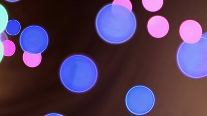 Soft blue pink colorful lights bokeh swirl and dance in a mesmerizing display. The vibrant hues create a calm, soothing atmosphere for evening enjoyment. Holiday background